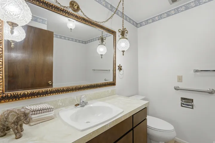 Bathroom featuring a vanity with an integrated sink, a large ornate framed mirror, and a toilet