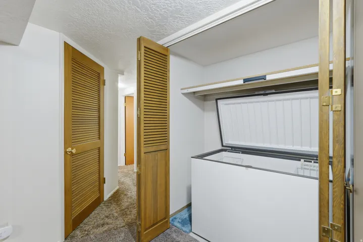 White walls with textured ceiling and wood-finish louvered doors