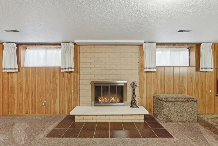 Brick fireplace with a raised hearth, stainless steel insert, and tile surround