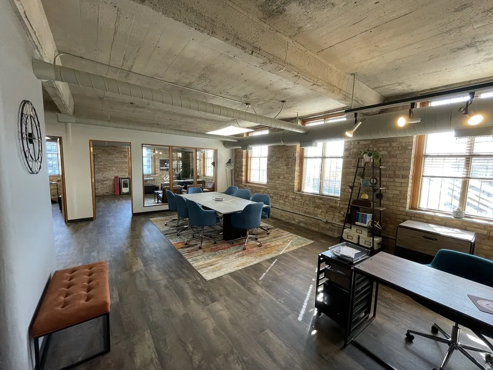 Game room with brick wall, dark wood finished floors, healthy amount of natural light, and a desk