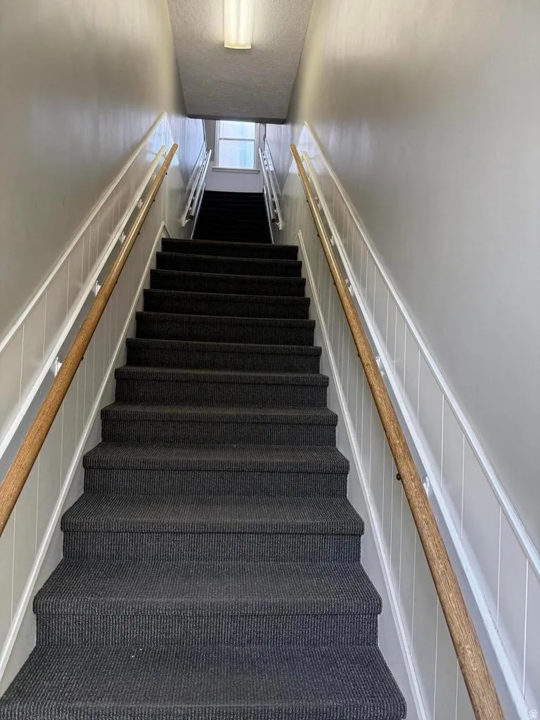 Stairs featuring wainscoting, a decorative wall, and a textured ceiling