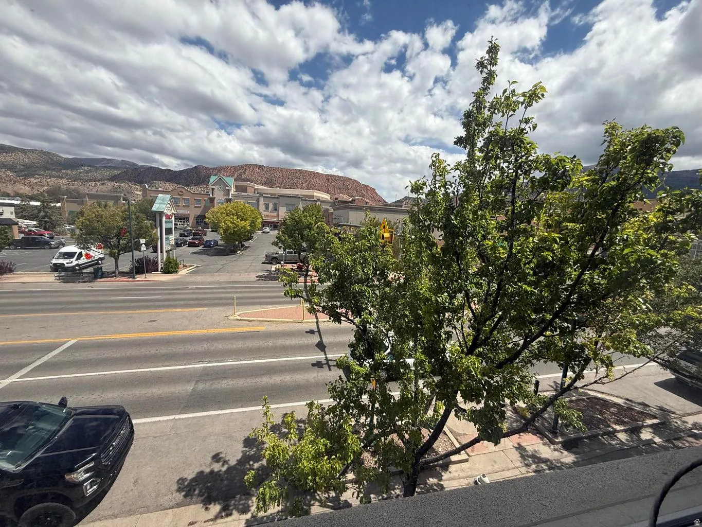 View of asphalt street with curbs, sidewalks, and a mountain view