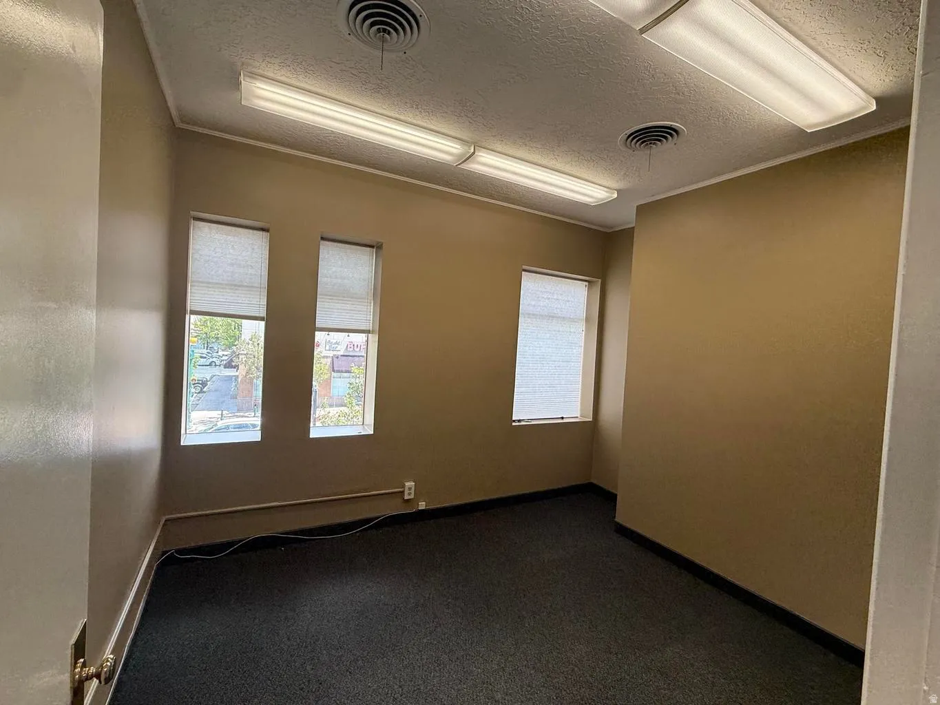 Unfurnished room featuring dark carpet, a textured ceiling, and crown molding