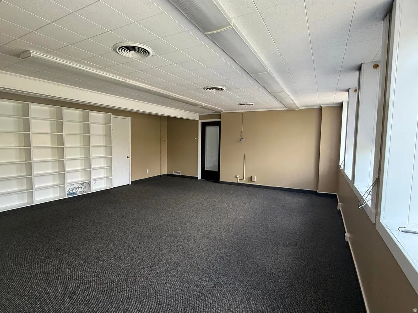 Spare room featuring dark colored carpet and baseboards