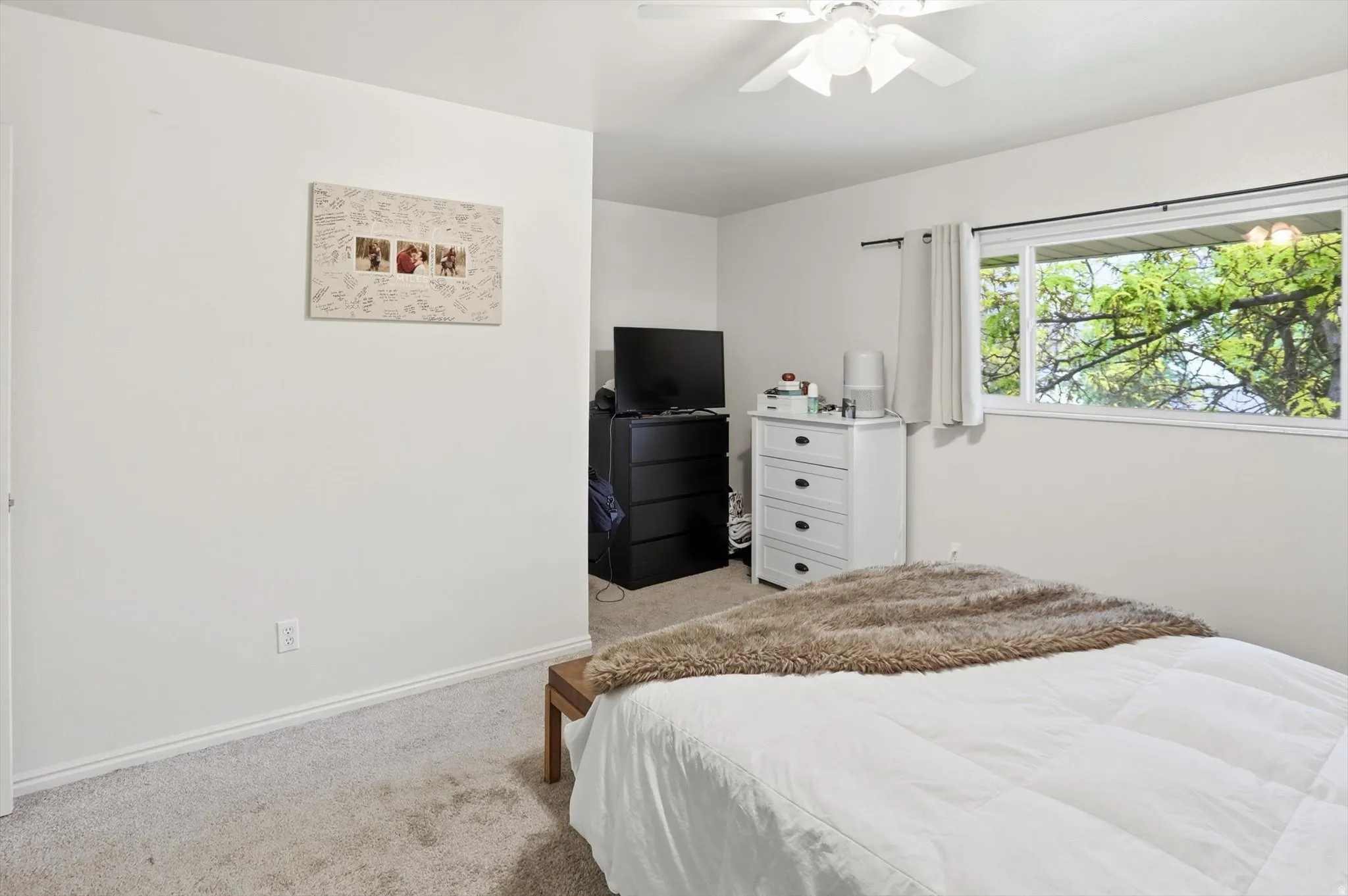 Bedroom with light carpet and a ceiling fan
