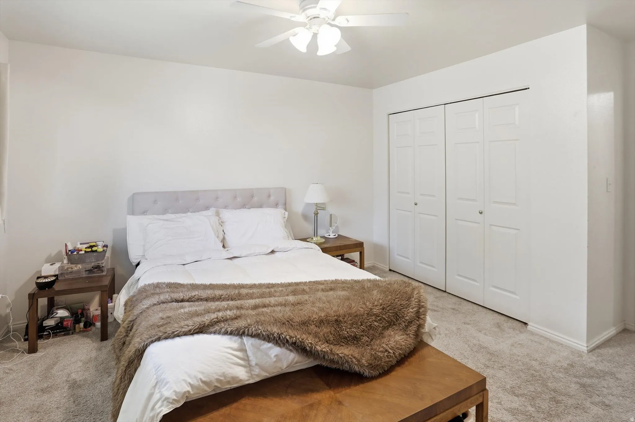 Bedroom with light colored carpet, a closet, and a ceiling fan