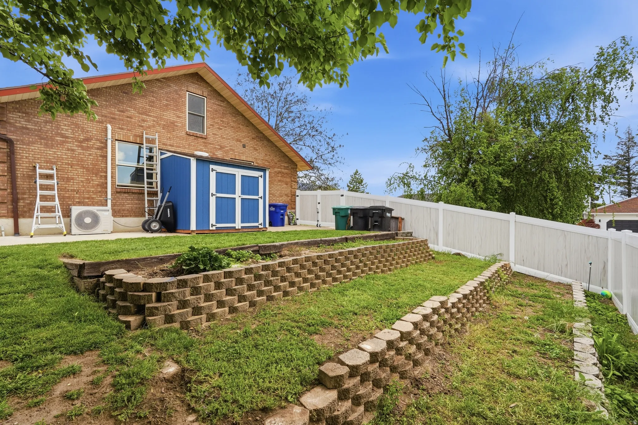 Rear view of property with a fenced backyard, brick siding, and a storage unit