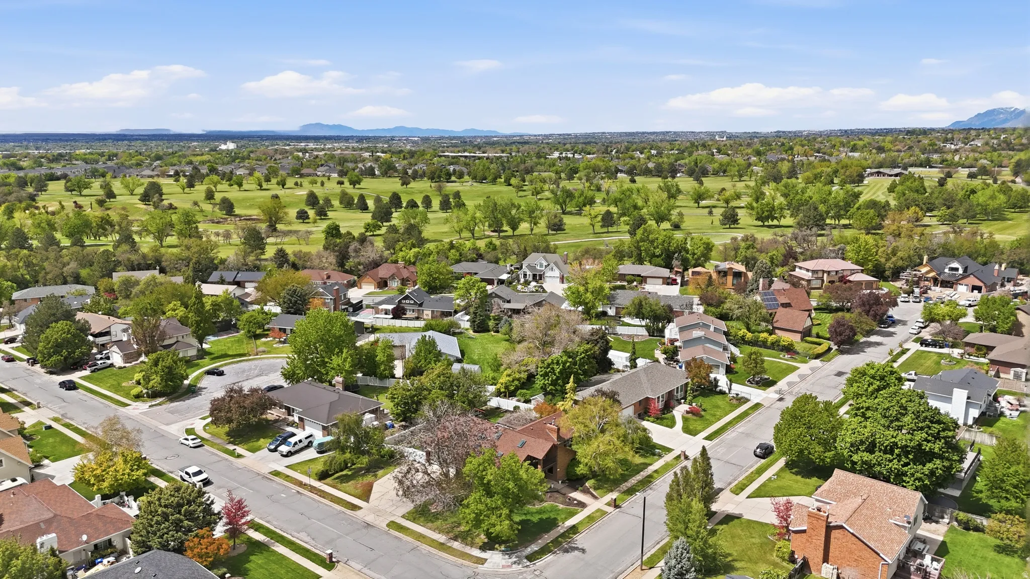 Aerial perspective of suburban area featuring a mountainous background and a golf club