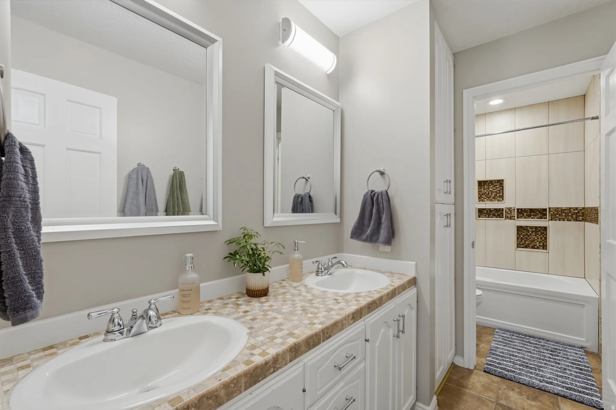 Main Floor Full bath featuring double vanity,  shower combination, and light tile patterned flooring