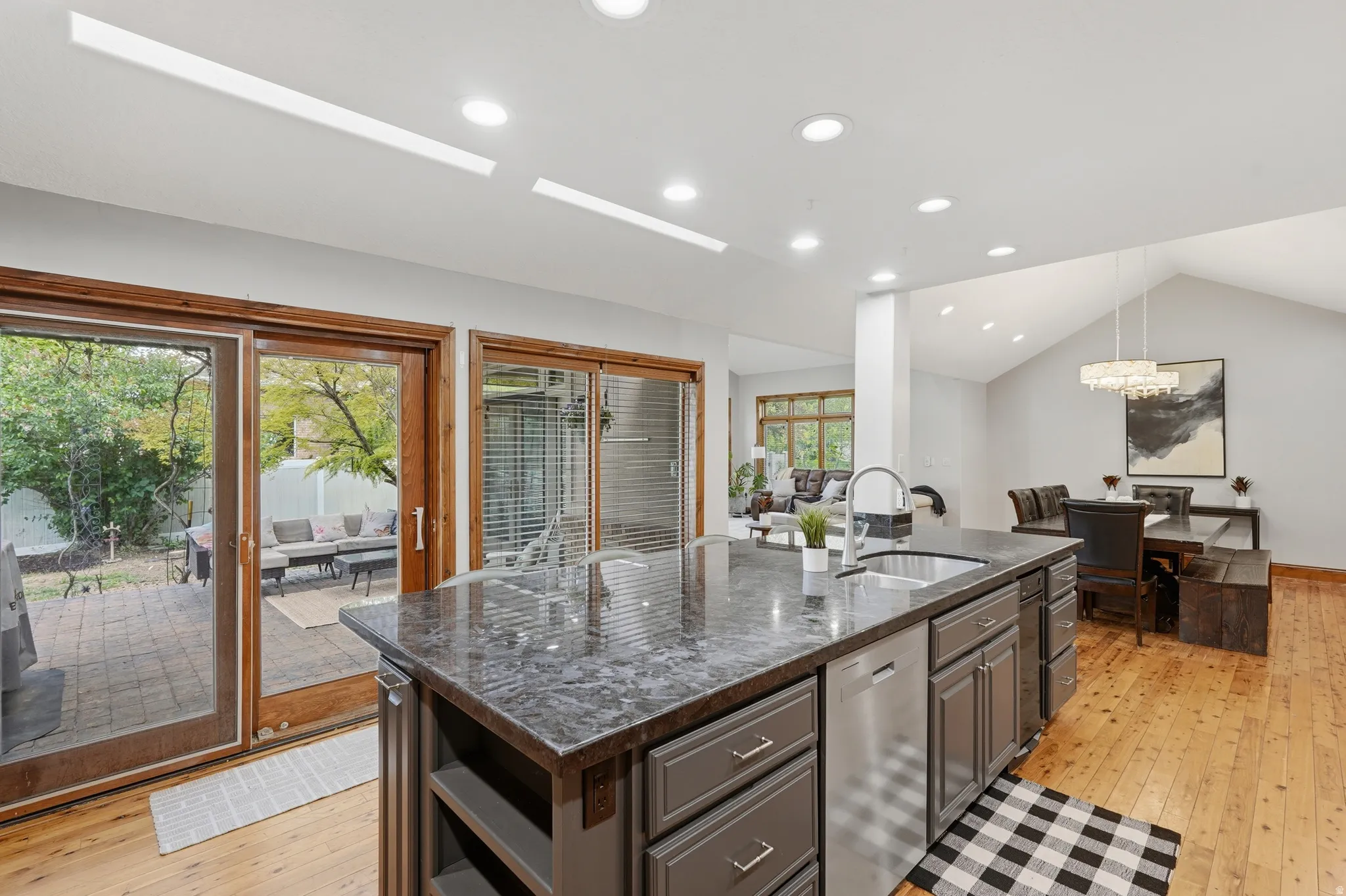 Dual tone kitchen featuring dual tone cabinets, 10' island,  granite counters, recessed lighting, and stainless steel appliances and access to outdoor patio.