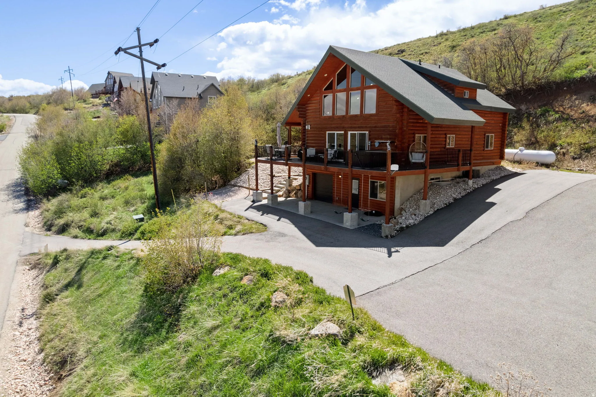 Rear view of house featuring a deck, log siding, an attached garage, and asphalt driveway