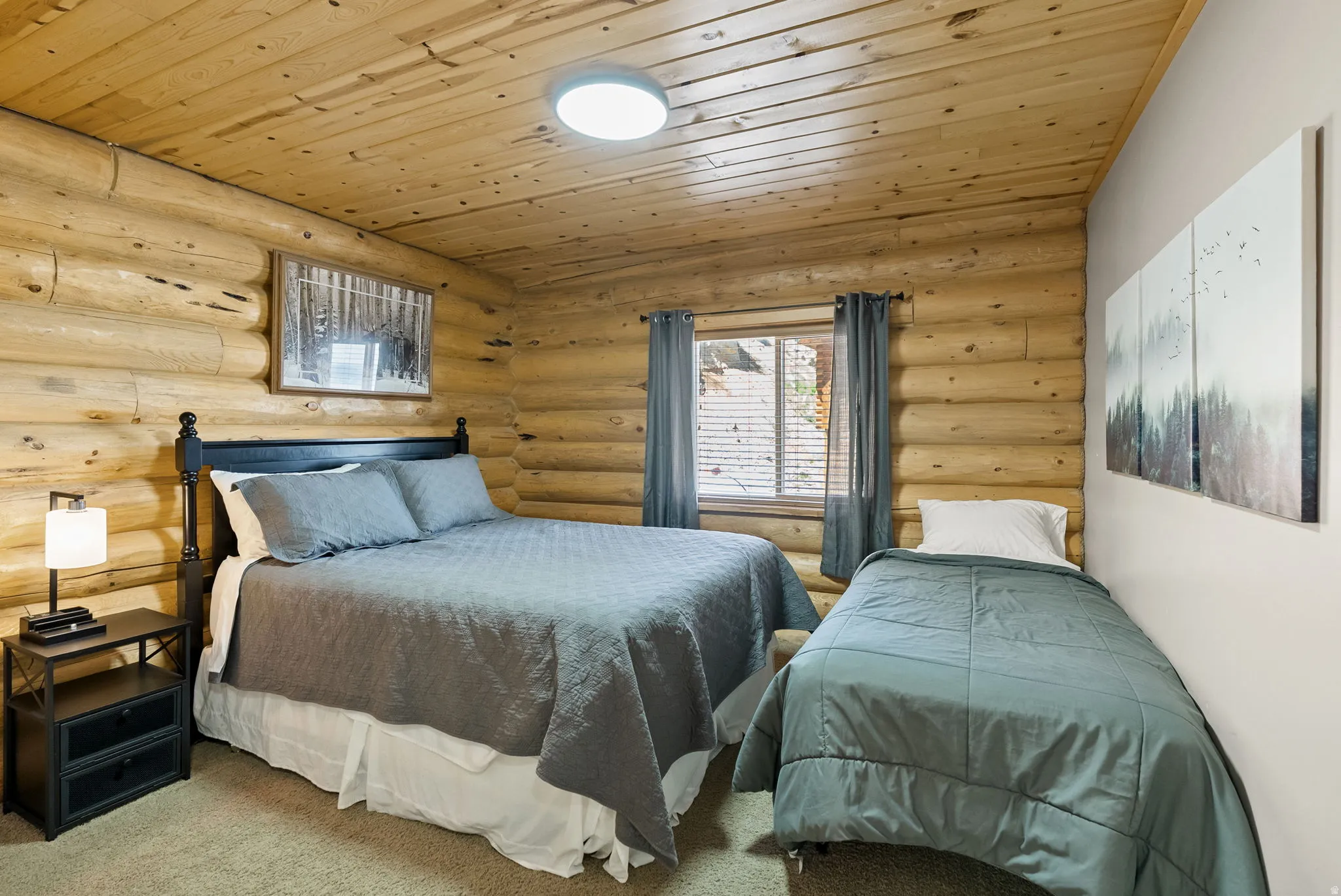 Carpeted bedroom with wooden ceiling and log walls