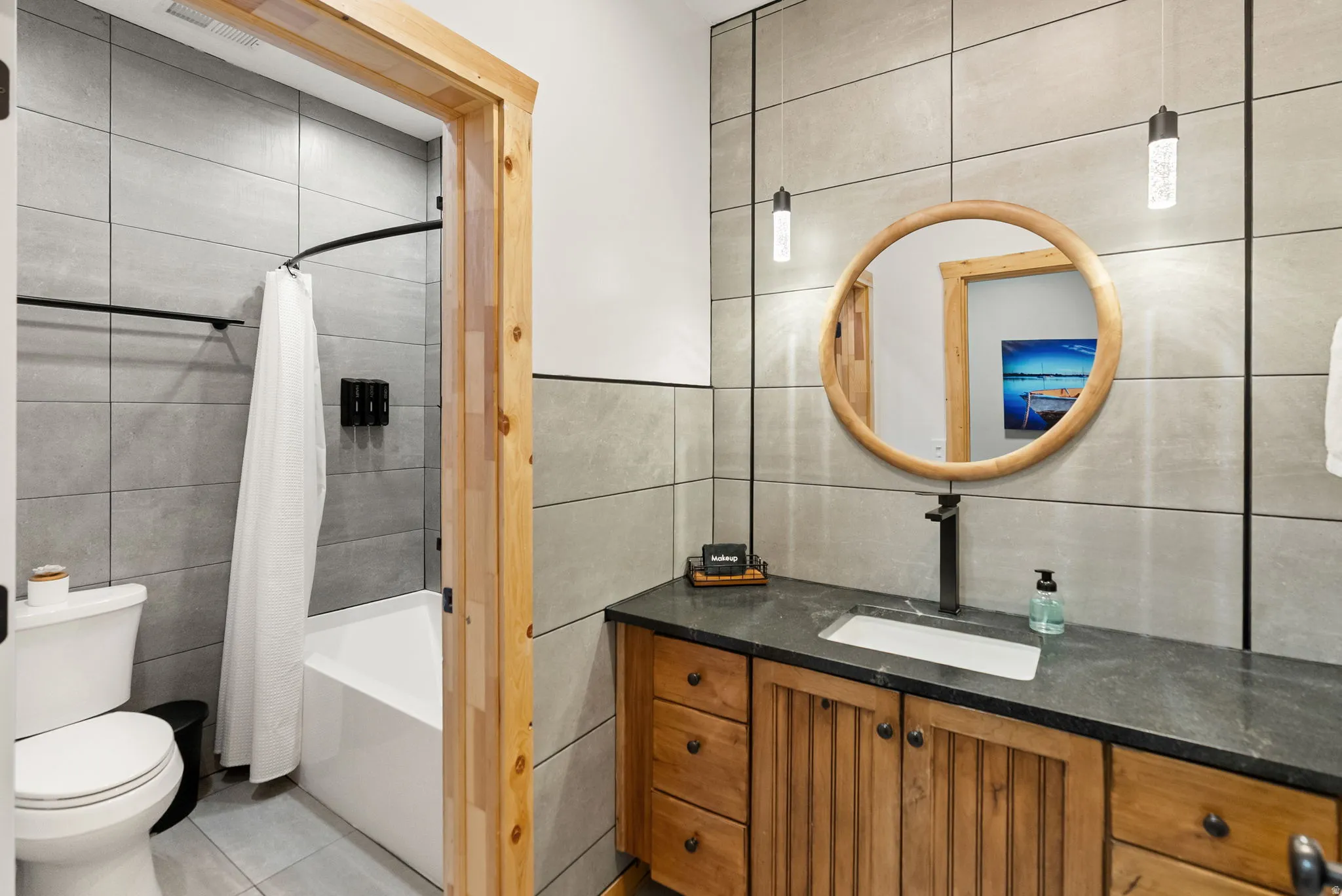 Bathroom with tile walls, vanity, shower / bath combo, and light tile patterned flooring