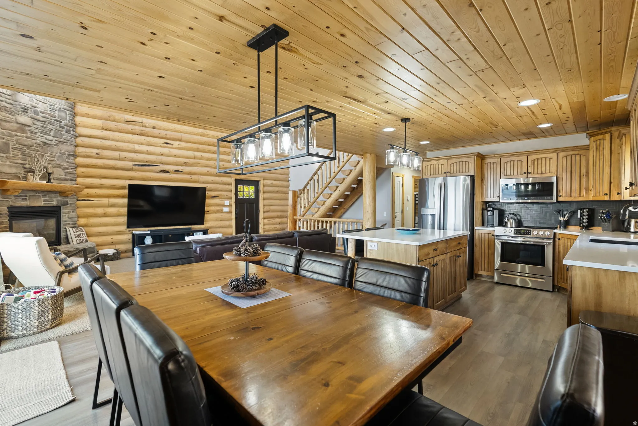 Dining space with log walls, wood ceiling, a fireplace, and dark wood-style floors