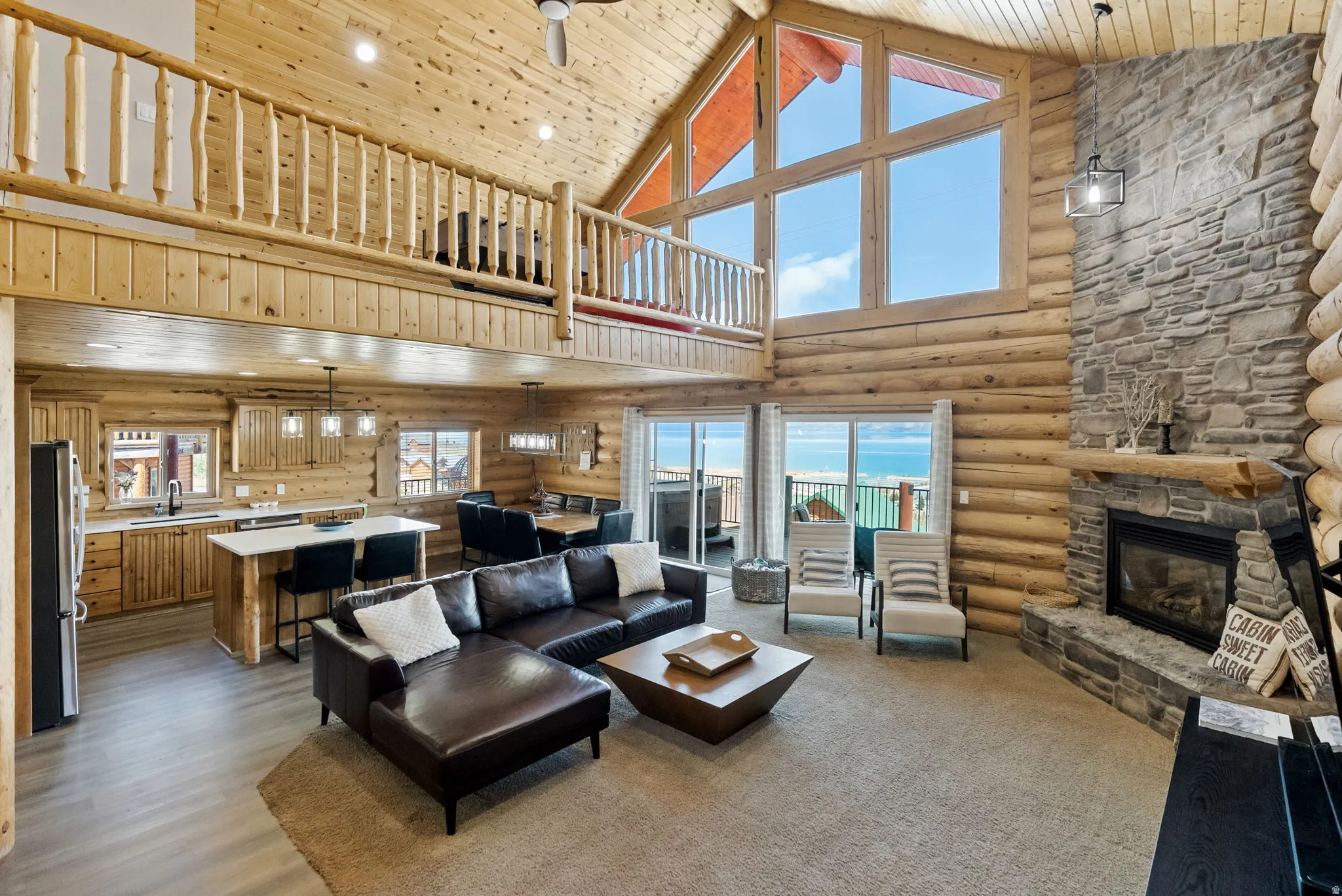 Living area featuring a high wood ceiling, a fireplace, log walls, ceiling fan, and light wood-style floors