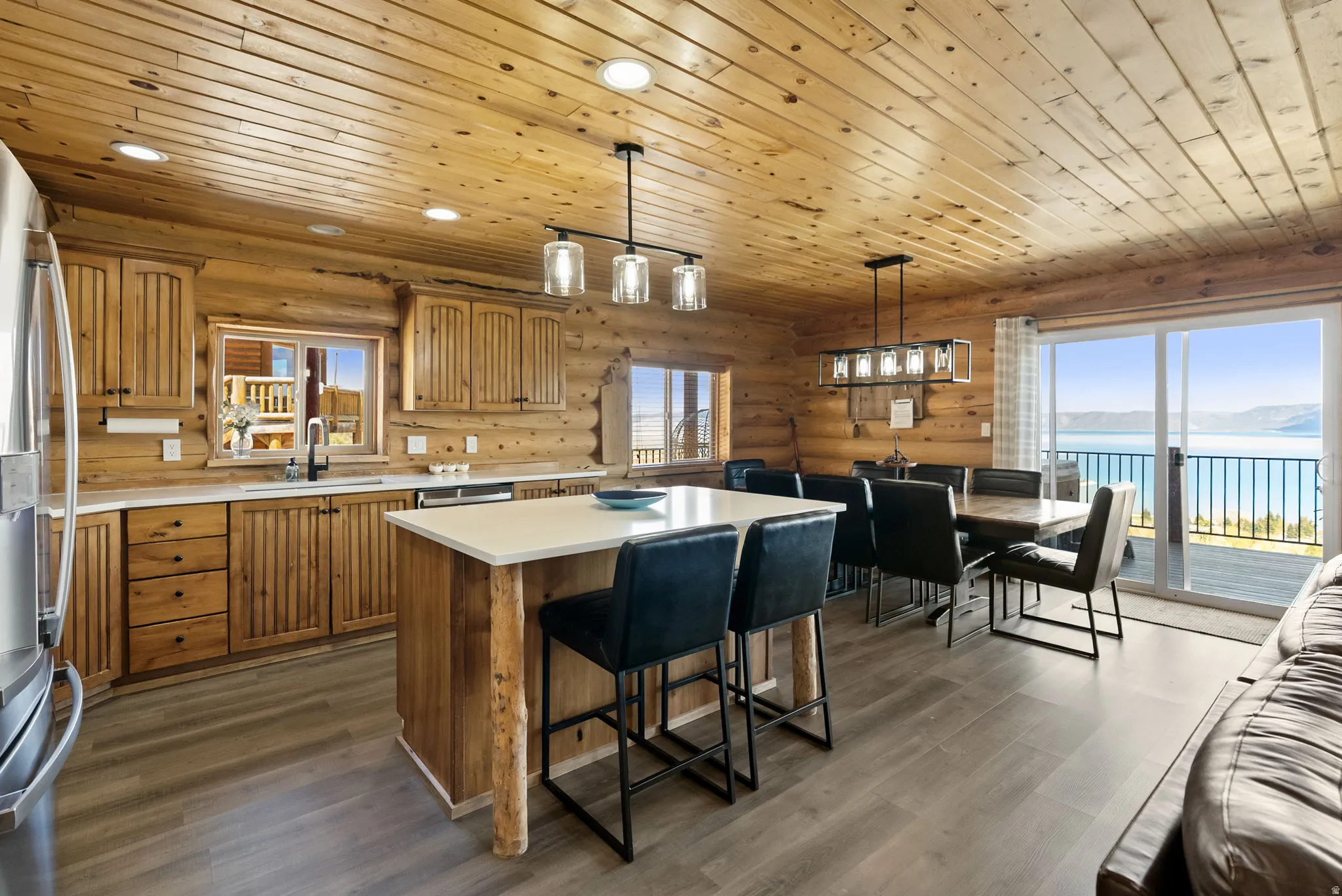 Kitchen with a water view, a kitchen island, decorative light fixtures, light countertops, and wood finish cabinetry