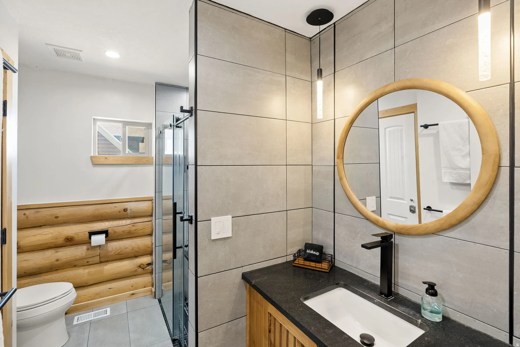 Bathroom with vanity, light tile patterned floors, a shower stall, tile walls, and rustic walls
