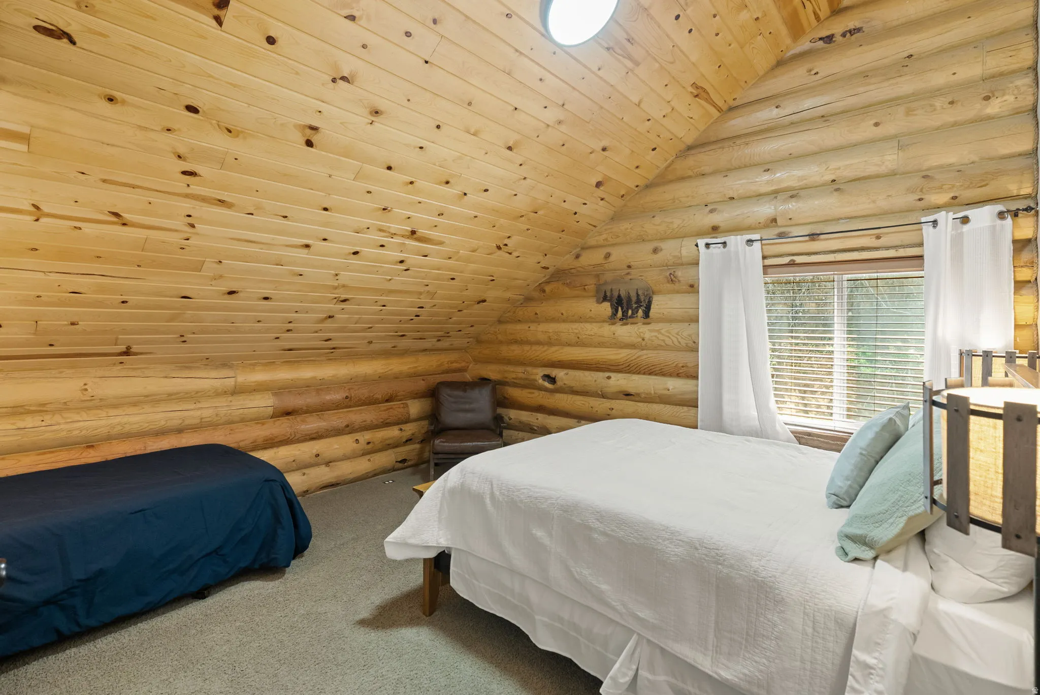 Carpeted bedroom featuring rustic walls and a vaulted wood ceiling