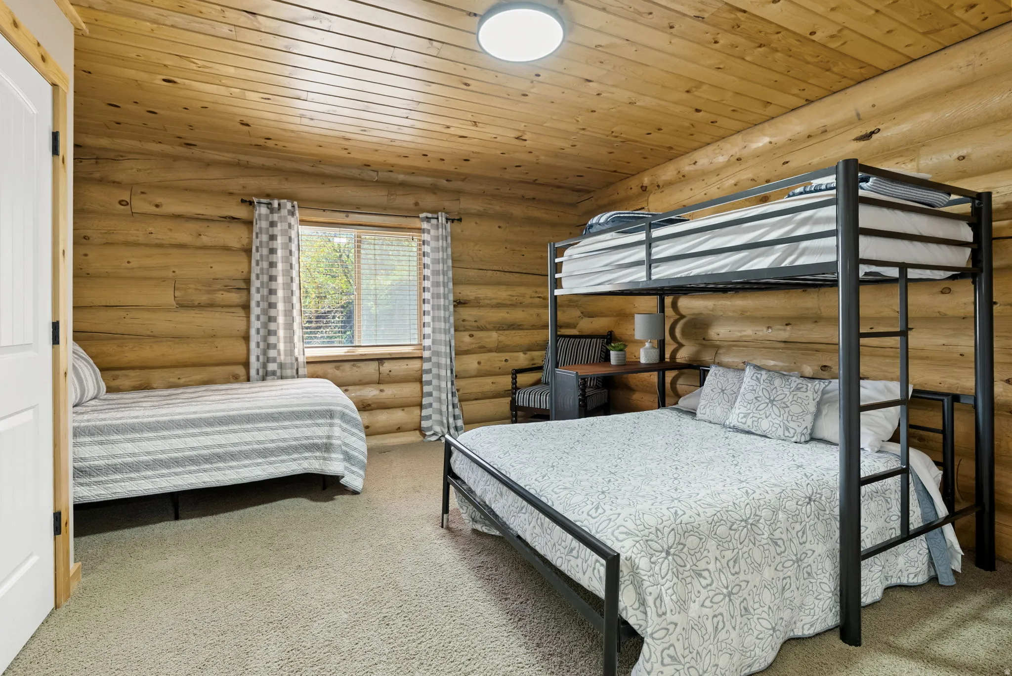 Bedroom featuring wooden ceiling, carpet floors, and rustic walls