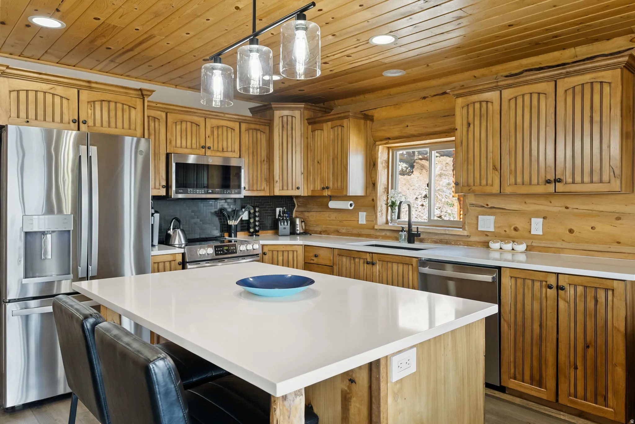 Kitchen with stainless steel appliances, a breakfast bar area, a kitchen island, pendant lighting, and wood ceiling