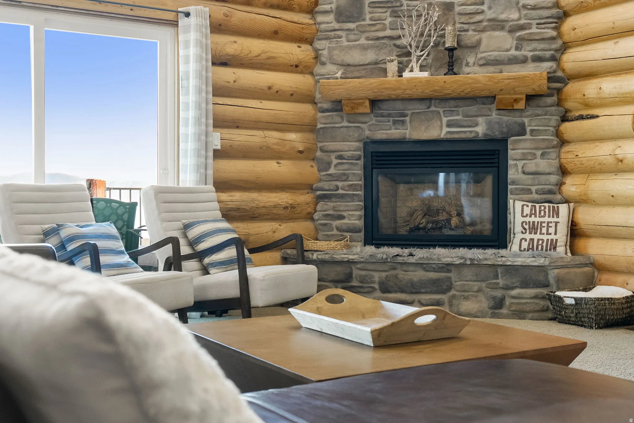 Carpeted living room featuring log walls and a fireplace
