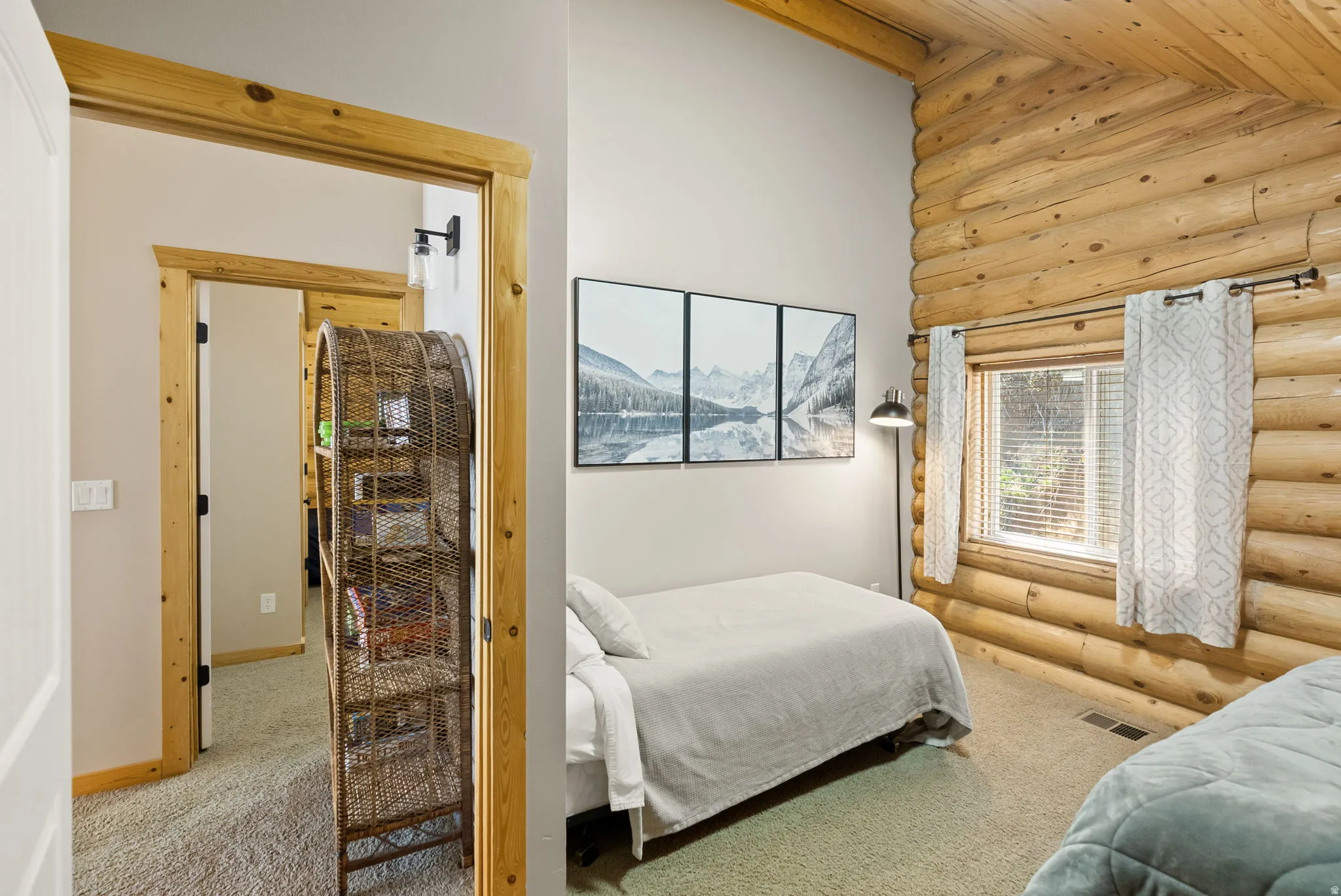 Bedroom with log walls, light carpet, and lofted ceiling