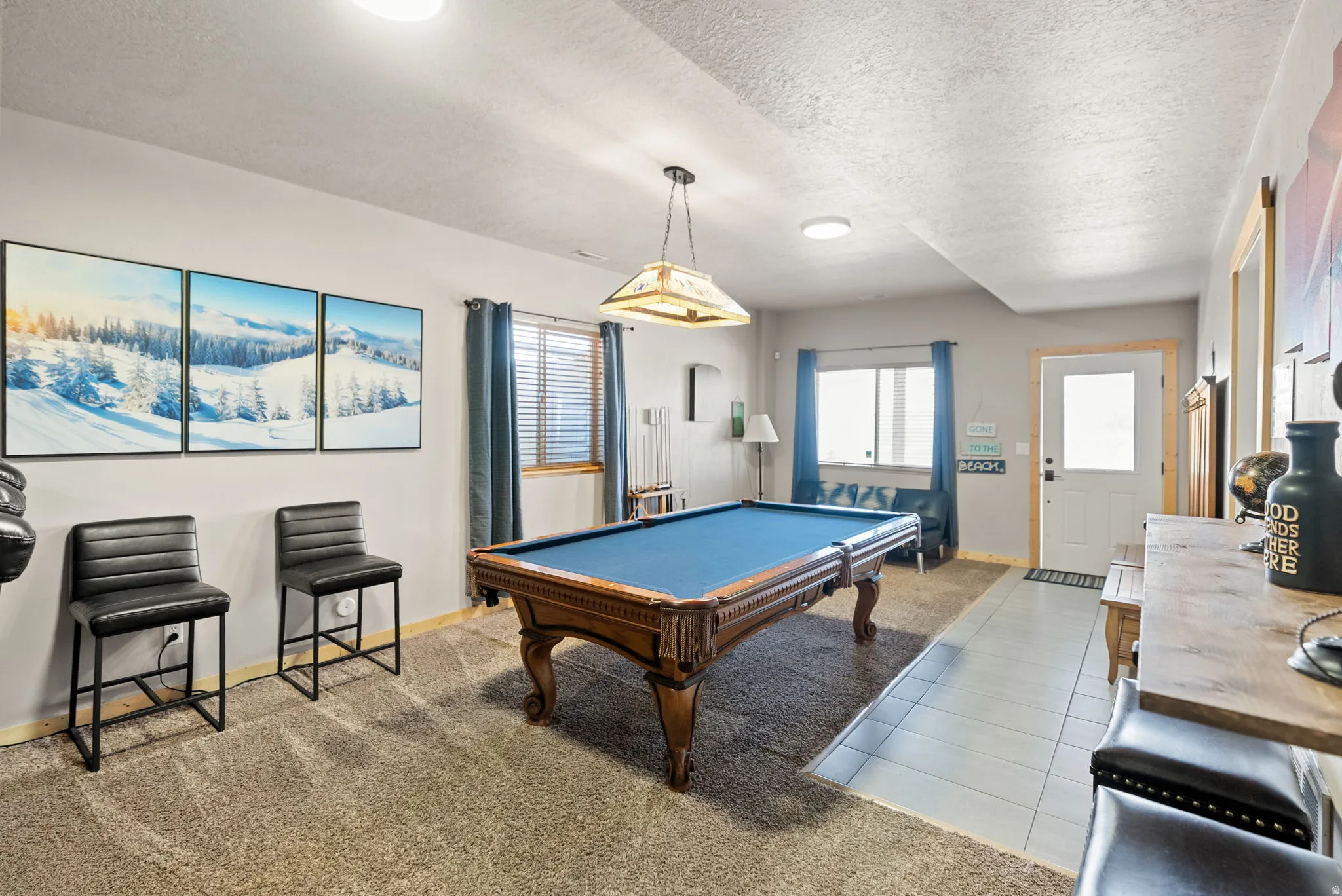 Playroom featuring pool table, a textured ceiling, light tile patterned floors, and light colored carpet