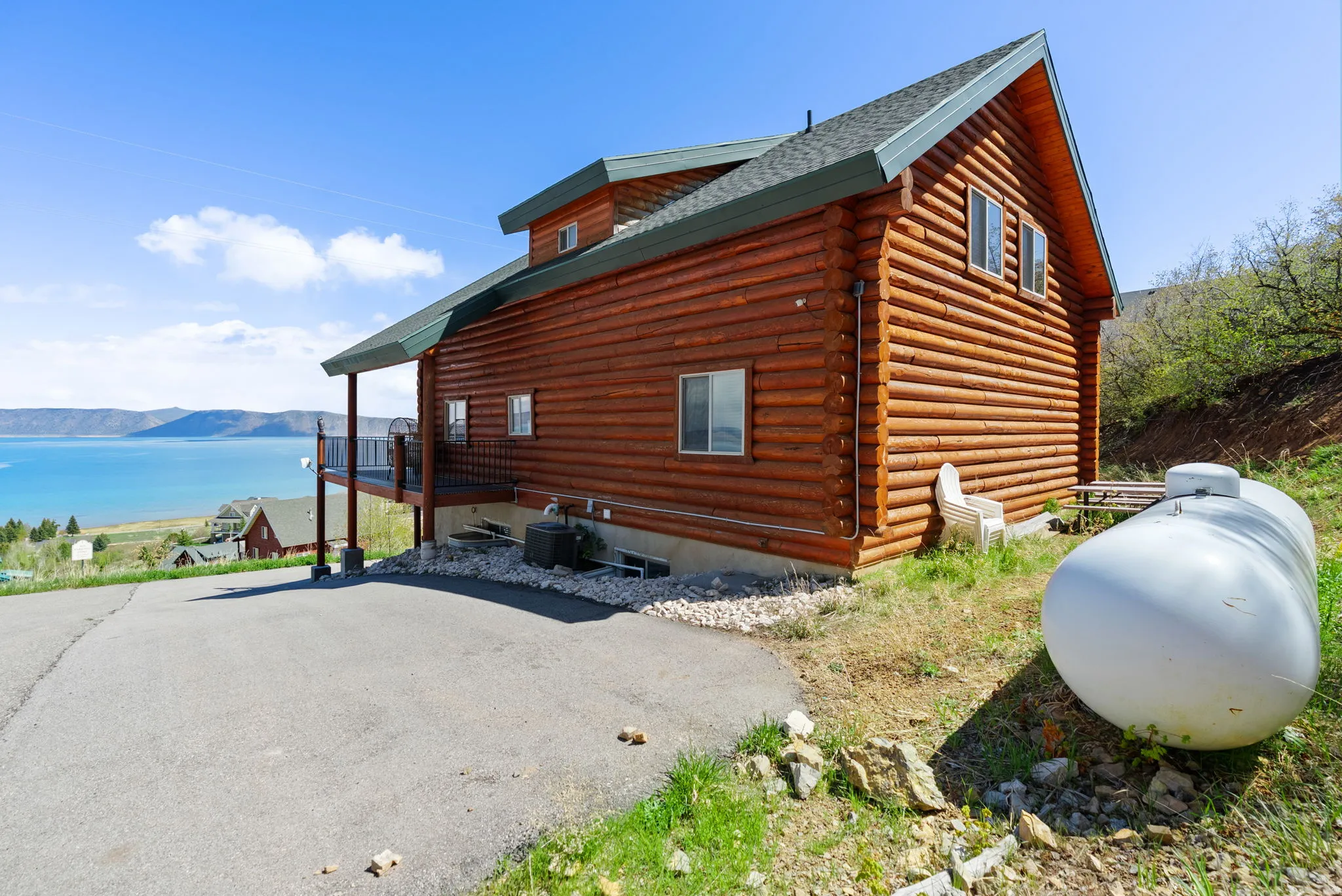 View of side of property with a deck with mountain view, log siding, and roof with shingles