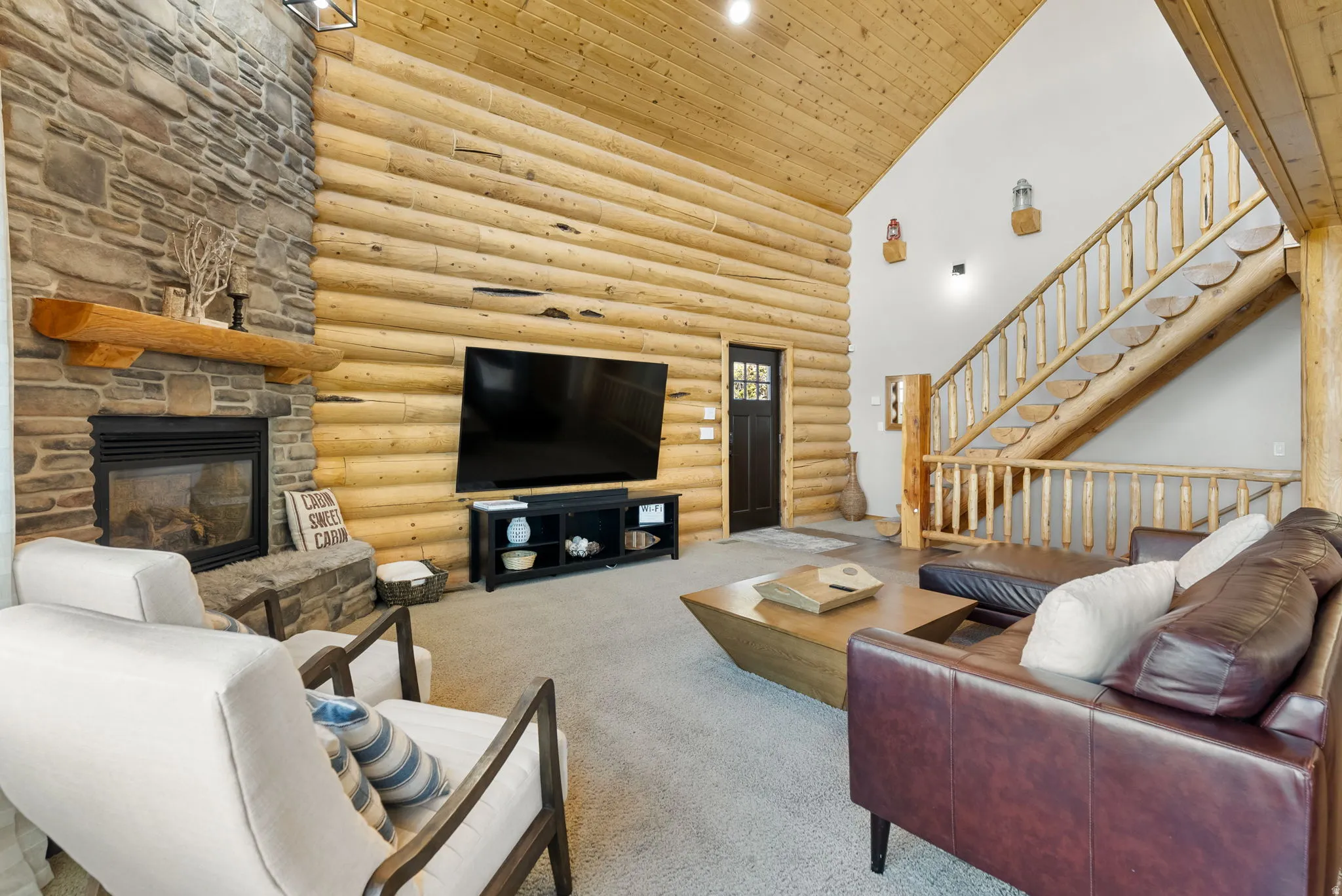 Carpeted living room featuring a vaulted wooden ceiling, log walls, and a fireplace