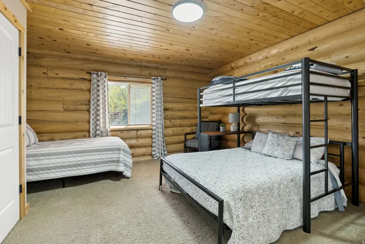 Bedroom featuring wooden ceiling, carpet floors, and rustic walls