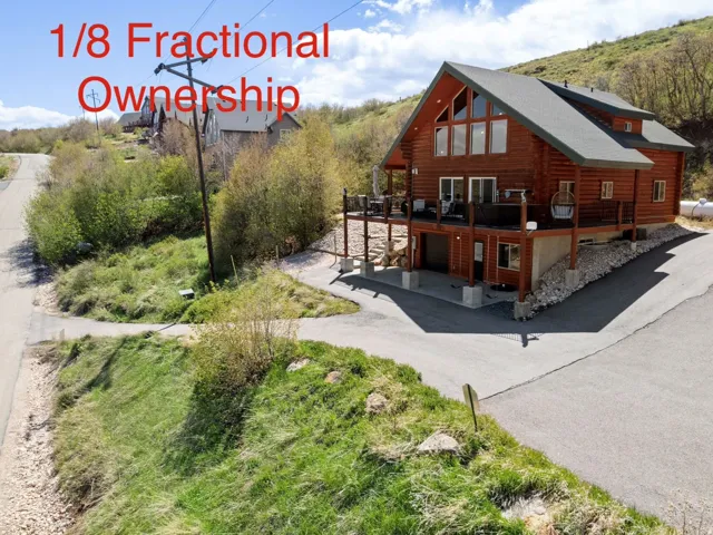 Rear view of property featuring a deck, a garage, log exterior, and asphalt driveway