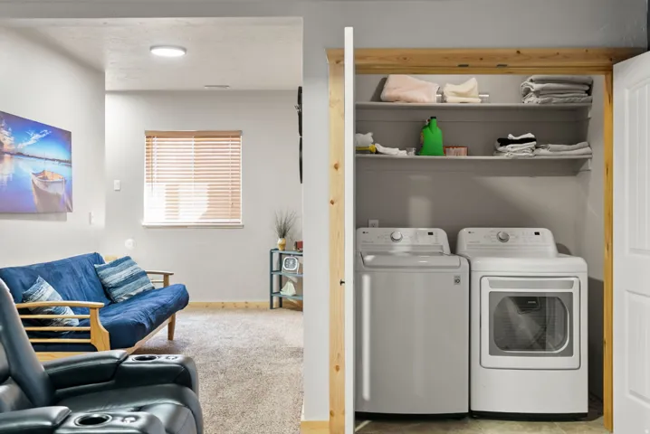 Laundry area with washing machine and dryer, light carpet, and a textured ceiling
