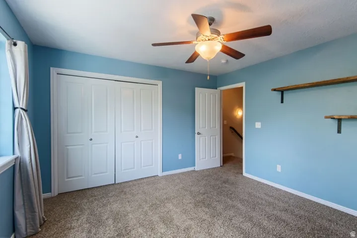 Unfurnished bedroom featuring carpet flooring, a closet, and a ceiling fan