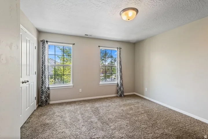 Carpeted spare room with baseboards and a textured ceiling