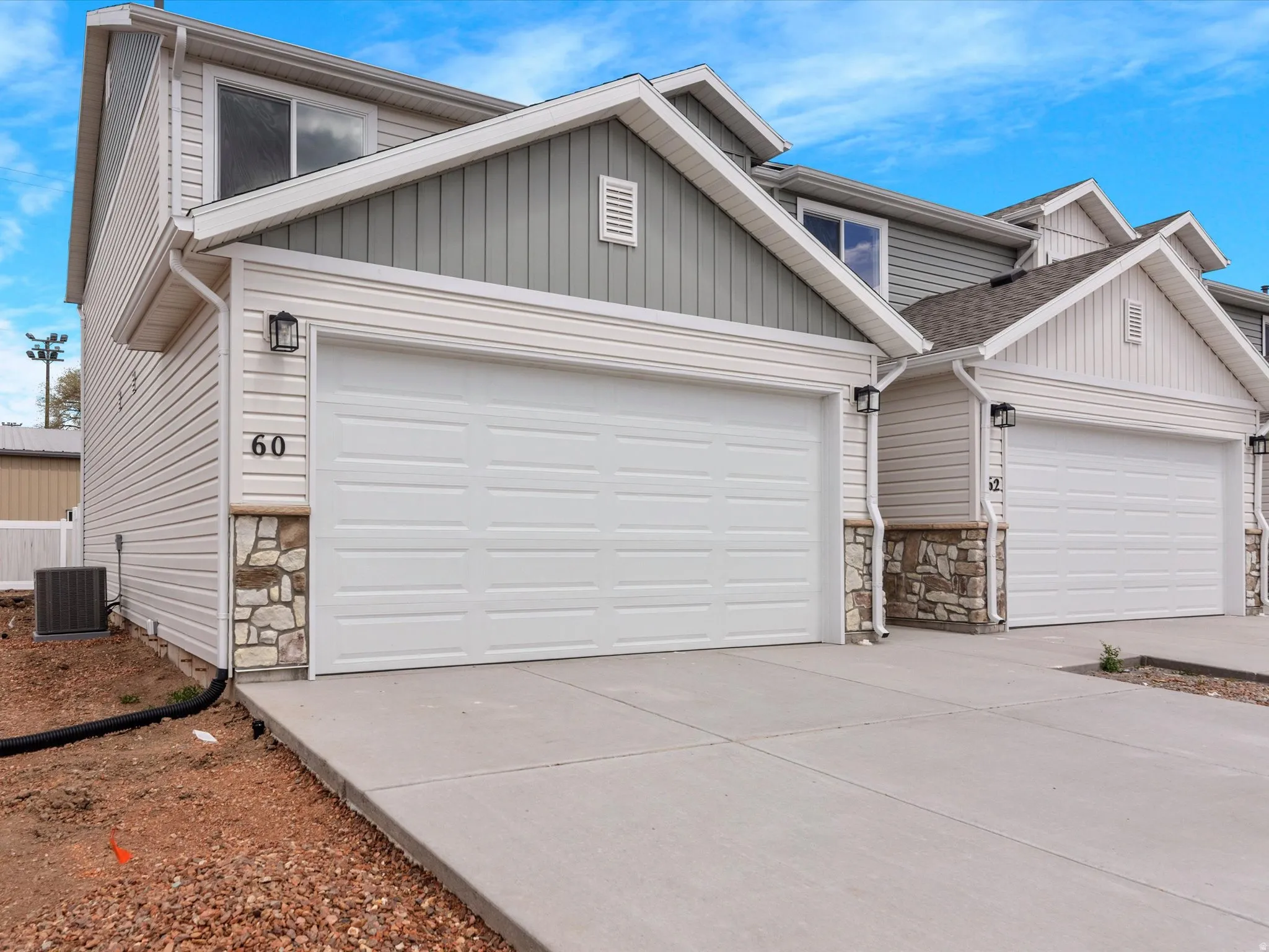 View of front of home featuring stone siding, an attached garage, and concrete driveway