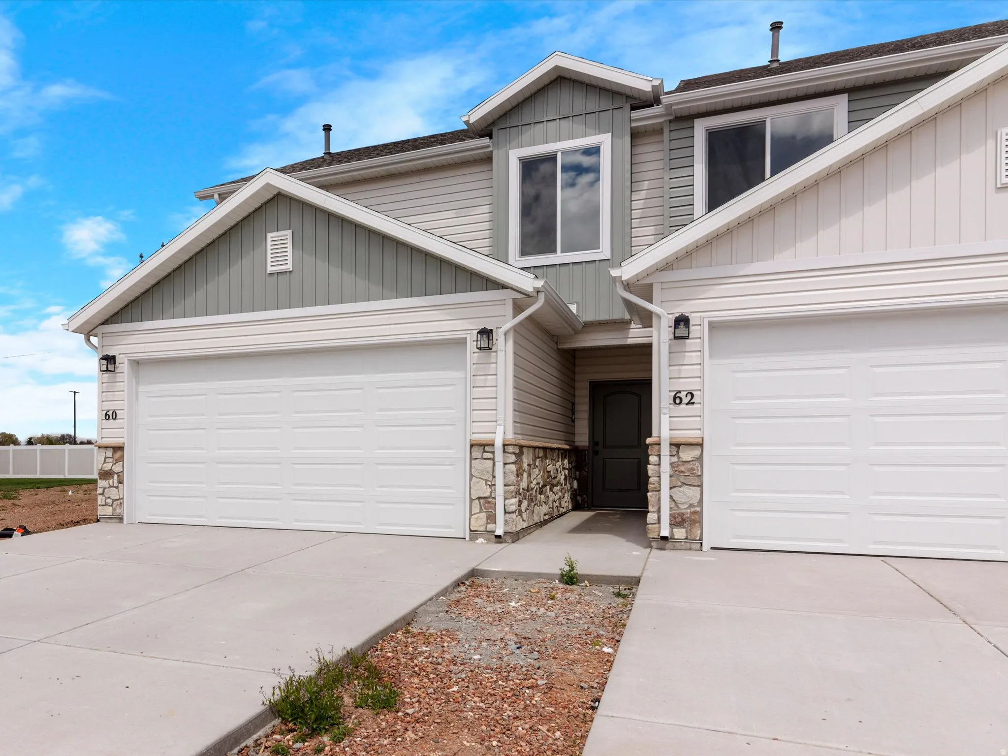 View of front facade with driveway, an attached garage, and stone siding