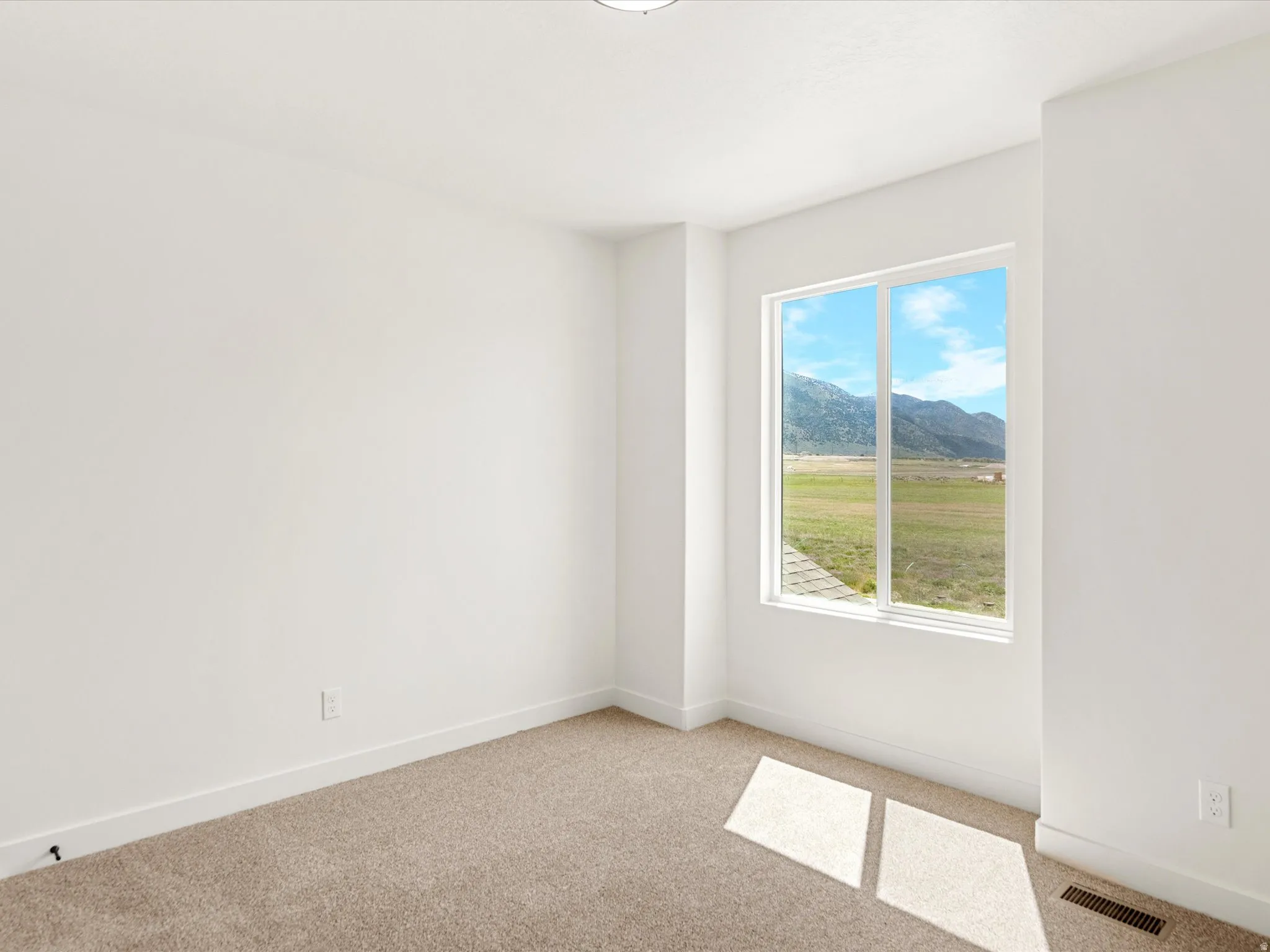 Spare room with a mountain view and light colored carpet