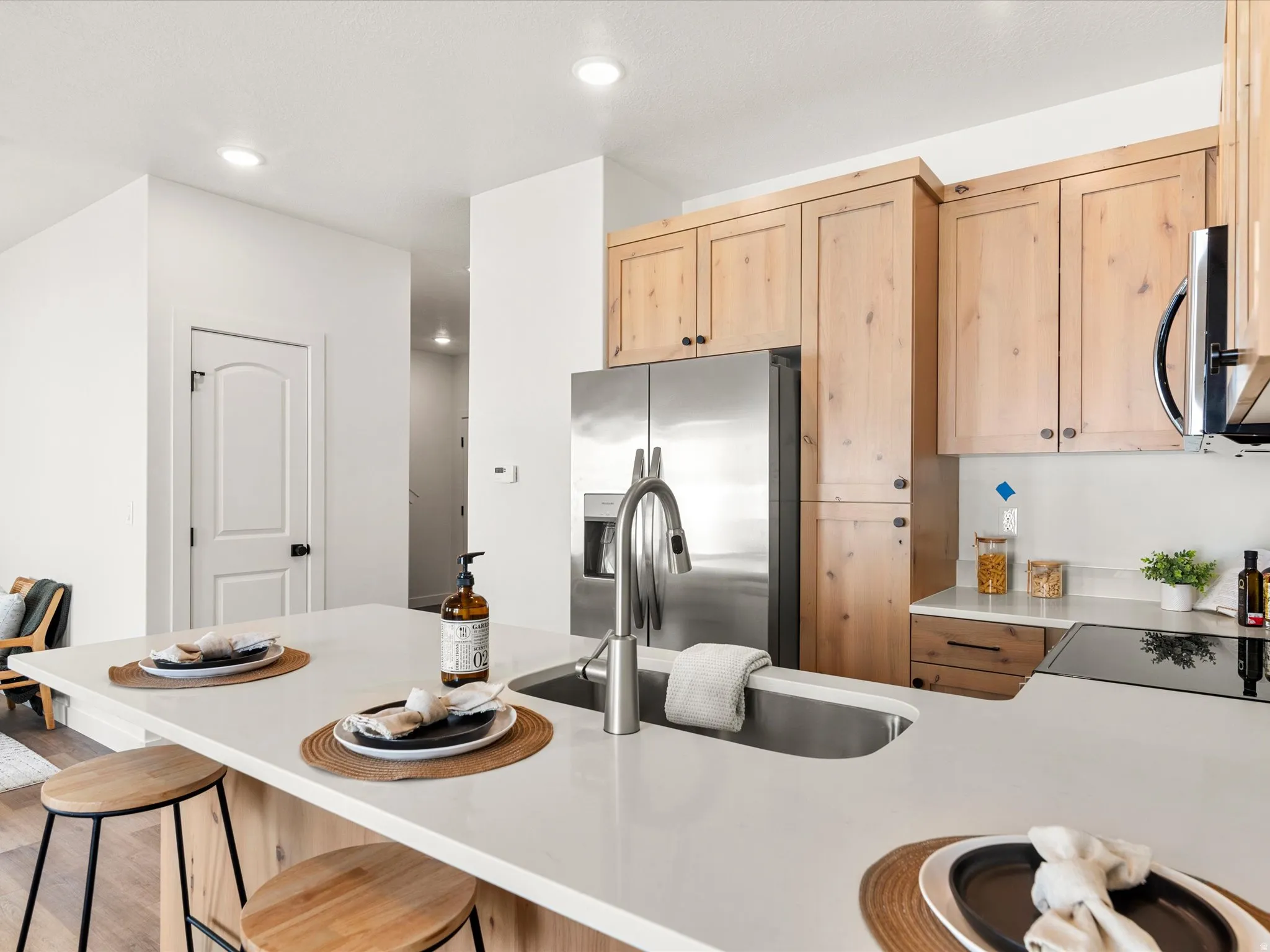 Kitchen featuring light wood finish cabinets, stainless steel appliances, recessed lighting, a breakfast bar area, and light stone countertops