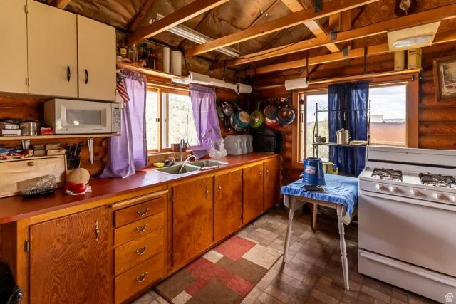 Kitchen featuring white appliances, vaulted ceiling, and wood finish cabinets