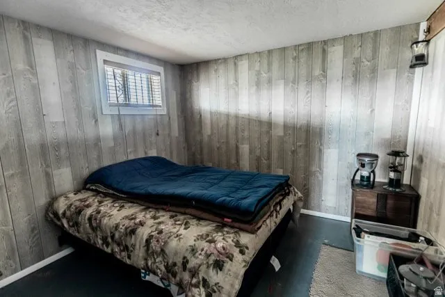 Bedroom with a textured ceiling and wood walls