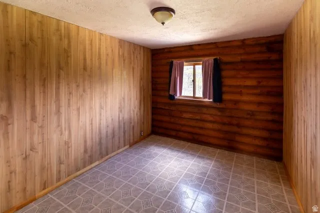 Unfurnished room with a textured ceiling and rustic walls