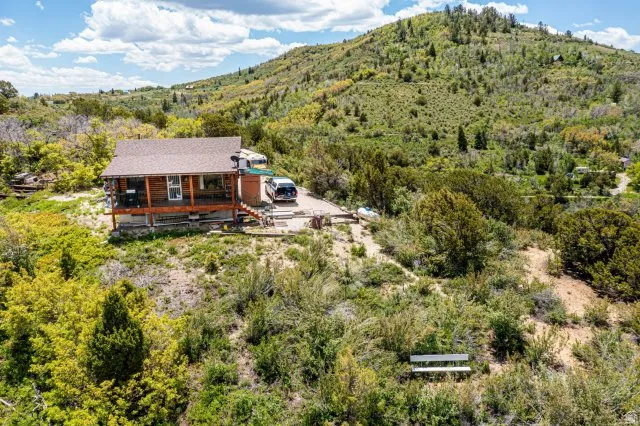 Aerial view of property and surrounding area featuring a heavily wooded area and mountains