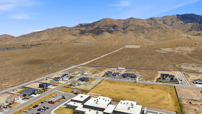 Aerial view of property and surrounding area featuring a mountain backdrop and nearby suburban area