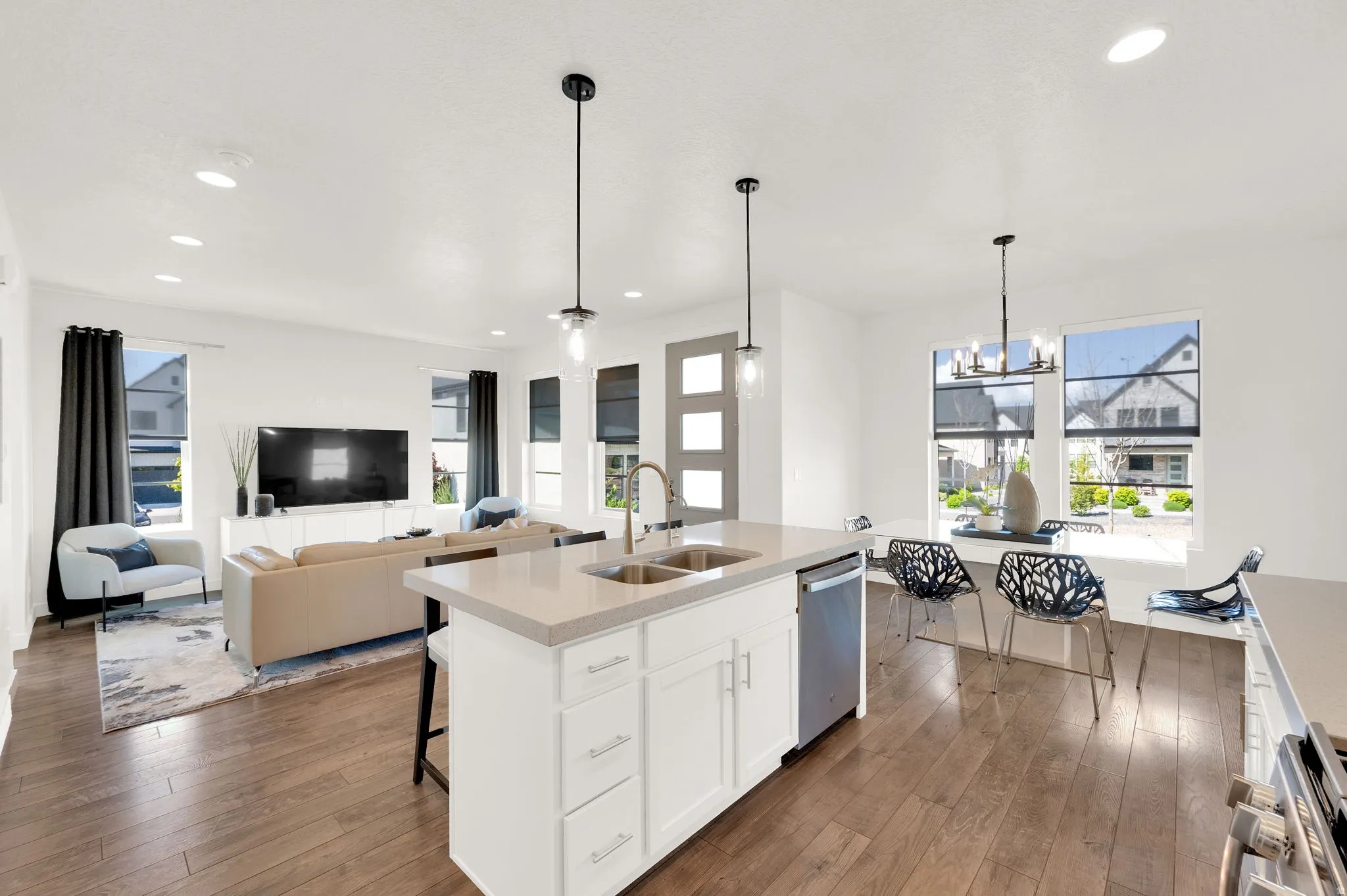 Kitchen with white cabinetry, open floor plan, dark wood-style floors, suspended lighting, and a center island with sink