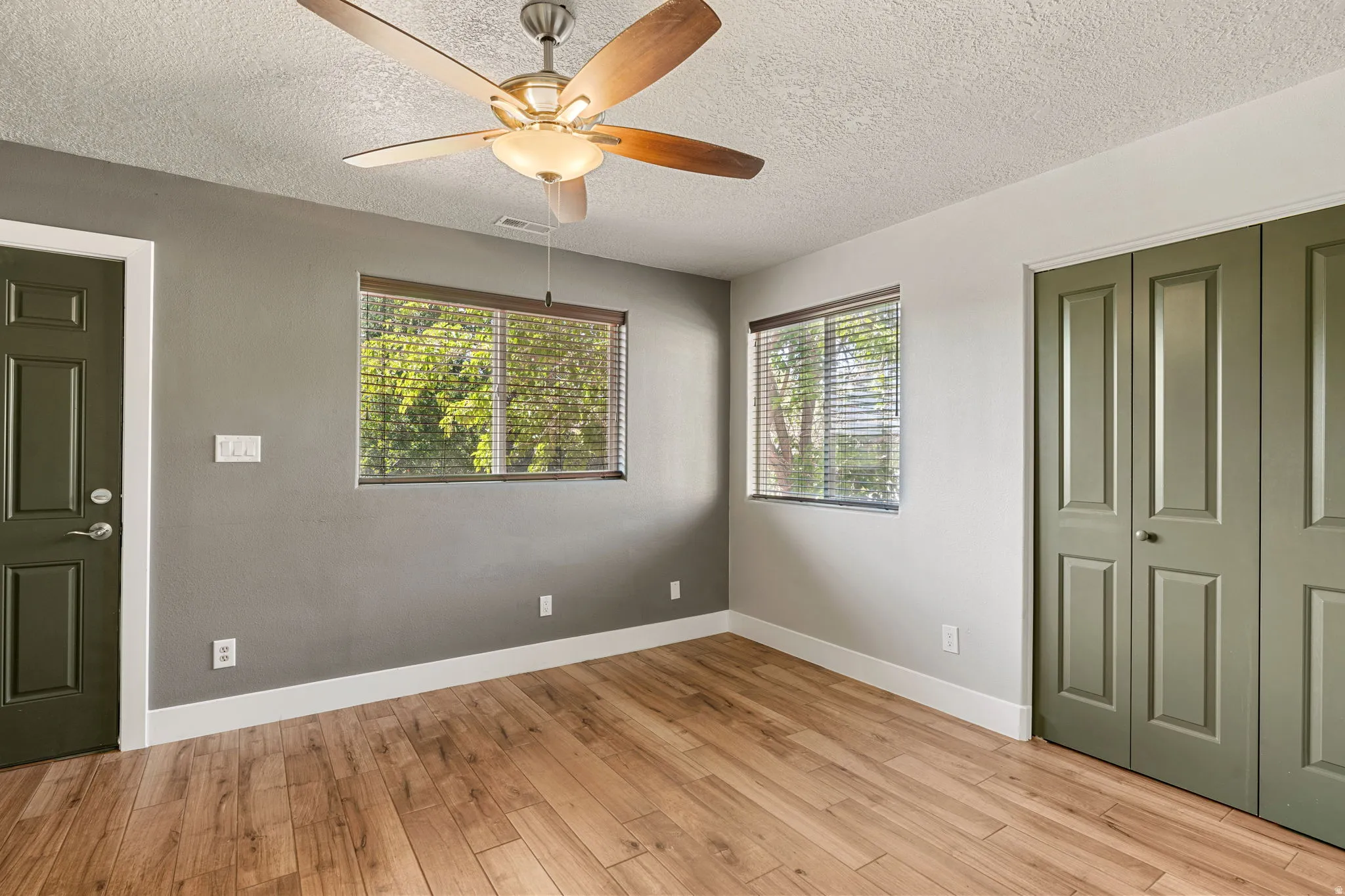 Unfurnished bedroom with light wood-style floors, a textured ceiling, a closet, and a ceiling fan