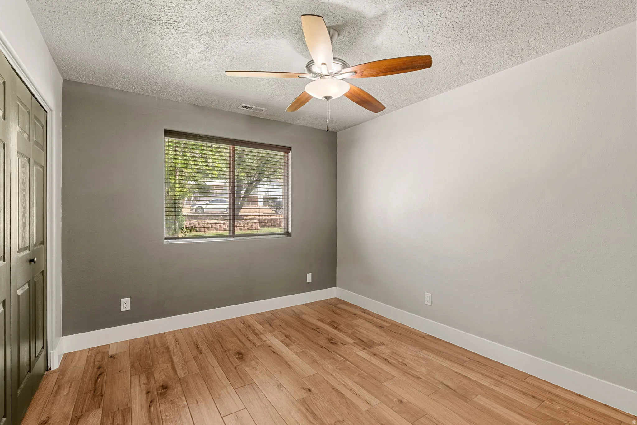 Unfurnished bedroom 2 with a closet, light wood-type flooring, a ceiling fan, and a textured ceiling