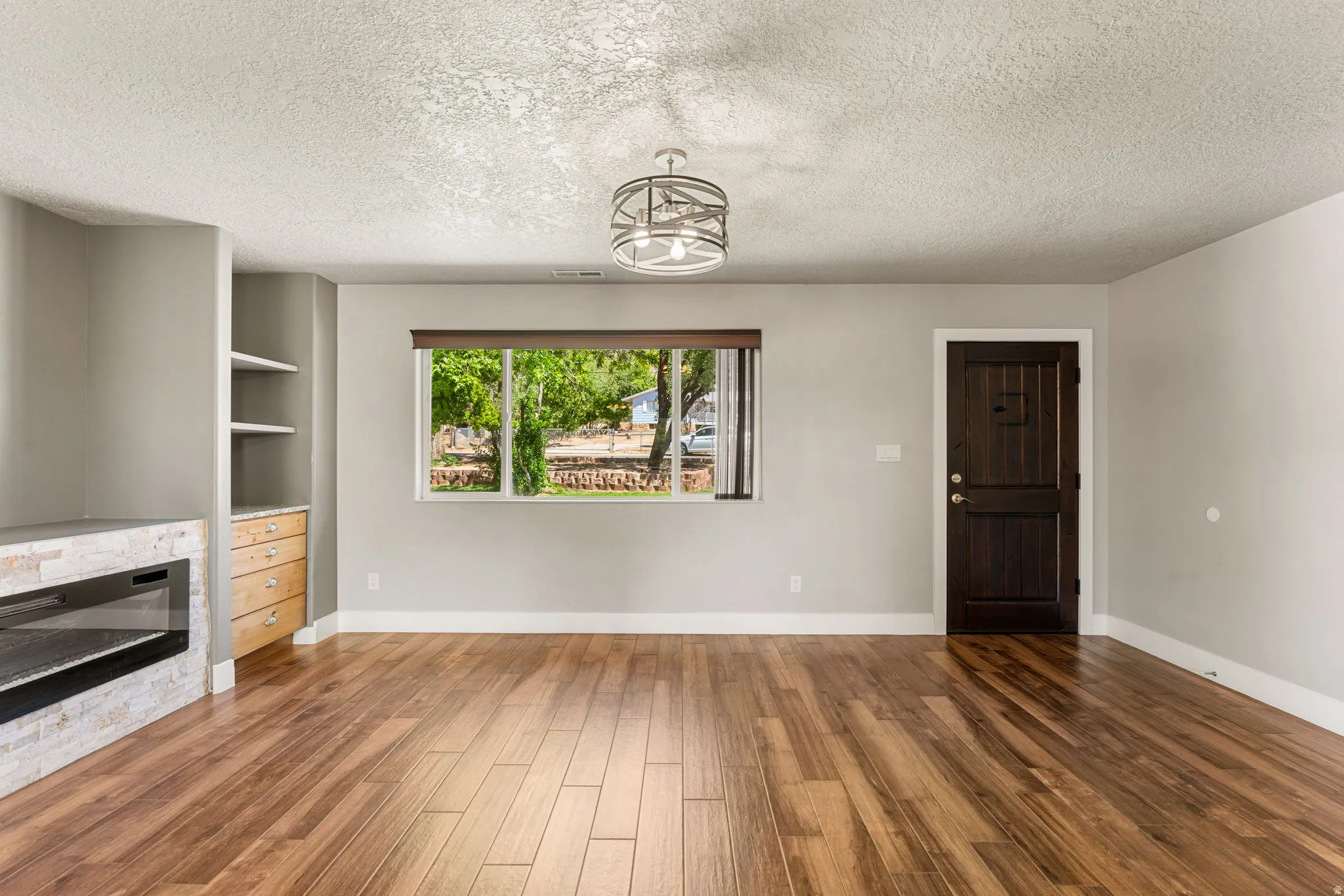 Unfurnished living room featuring a fireplace, a textured ceiling, and dark wood-style floors