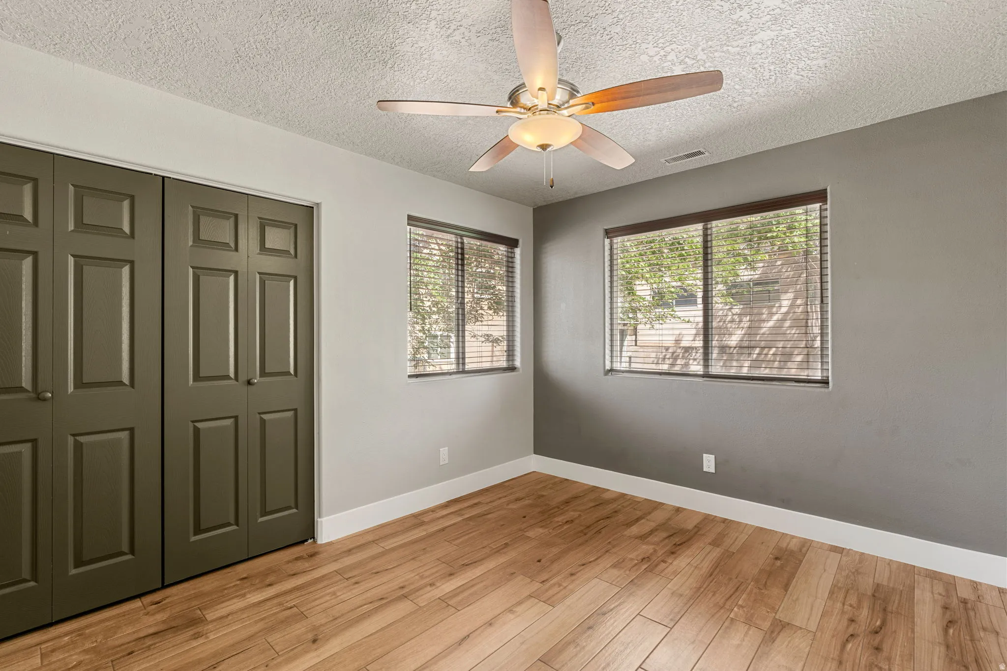 Unfurnished bedroom 4 with light wood finished floors, a closet, a ceiling fan, and a textured ceiling