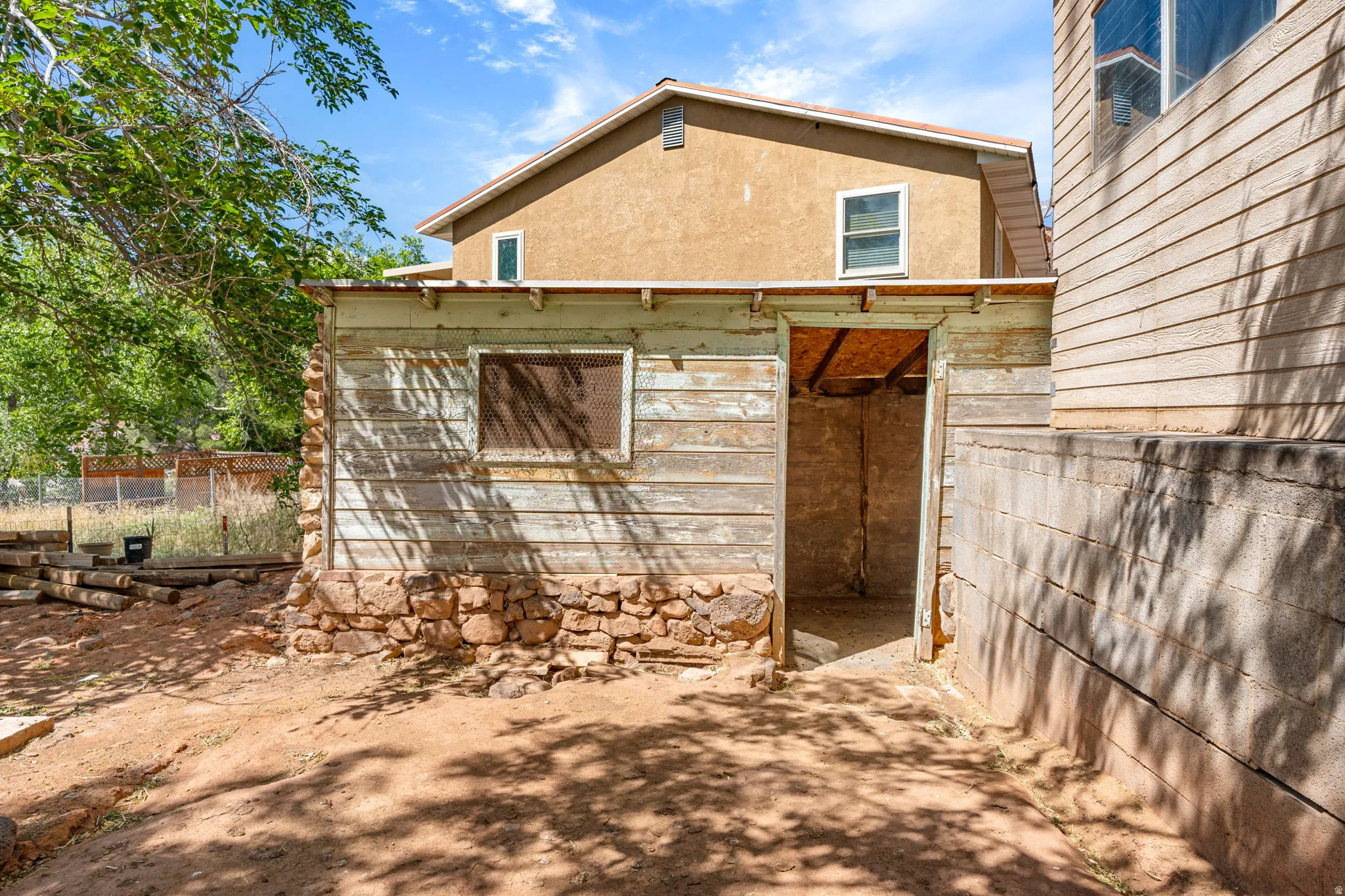 View of side of property featuring stucco siding chicken coop