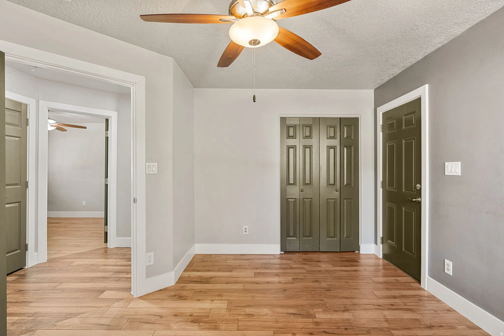 Unfurnished bedroom 3 featuring light wood-type flooring, a textured ceiling, a ceiling fan, and a closet